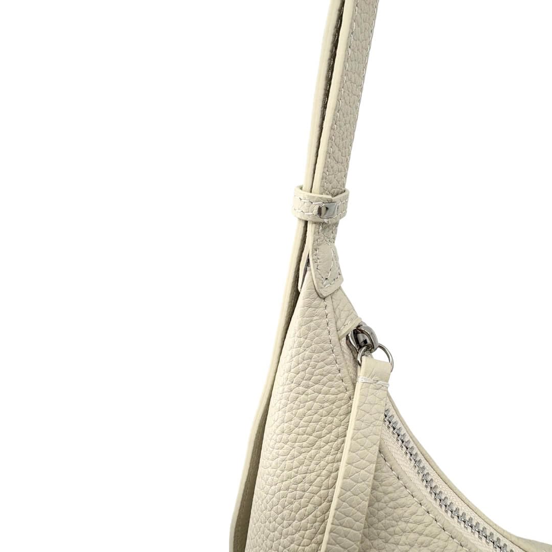 Close-up of a ivory ash handbag with a strap on a white background
