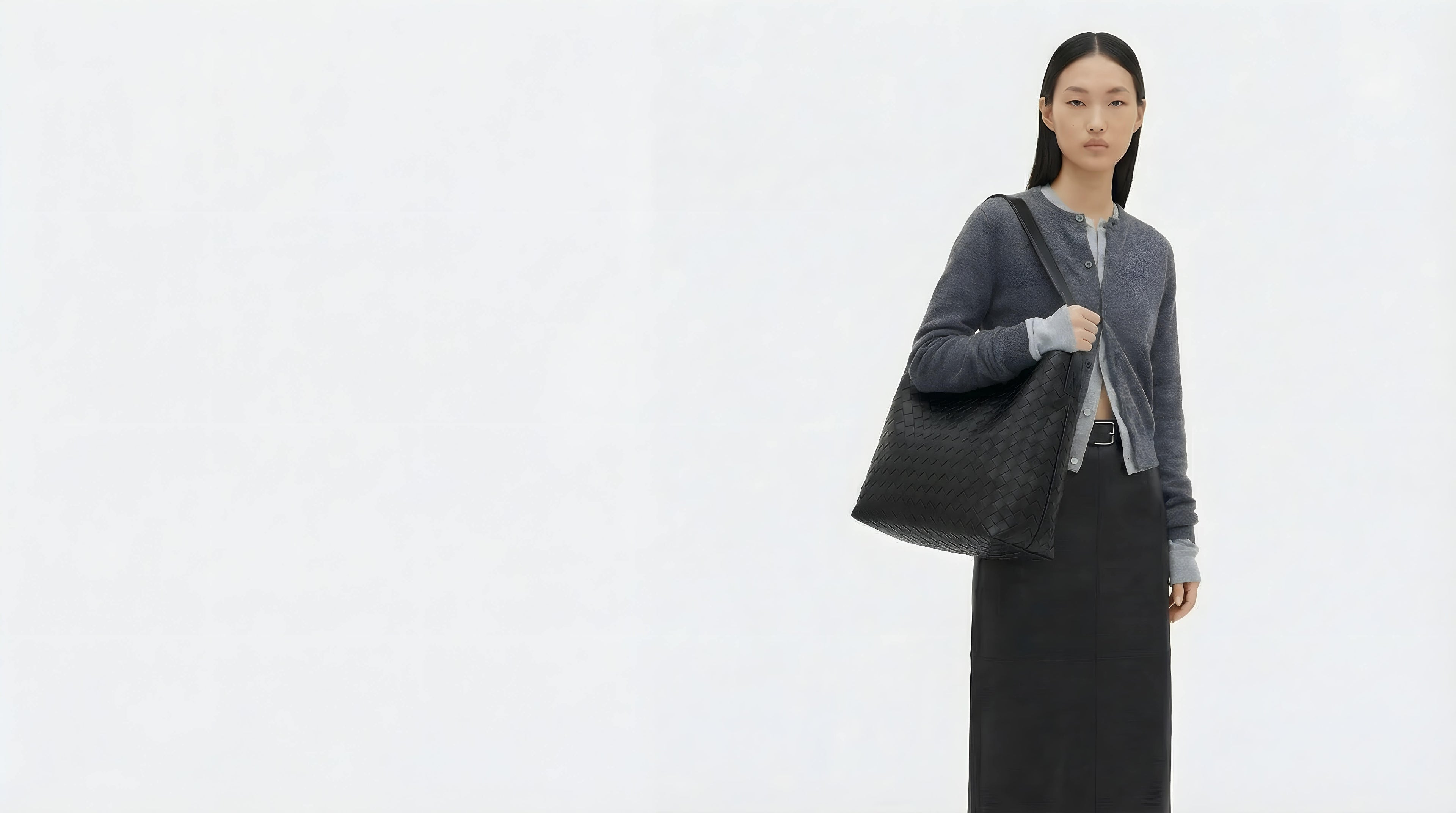 Woman holding a black tote bag against a white background